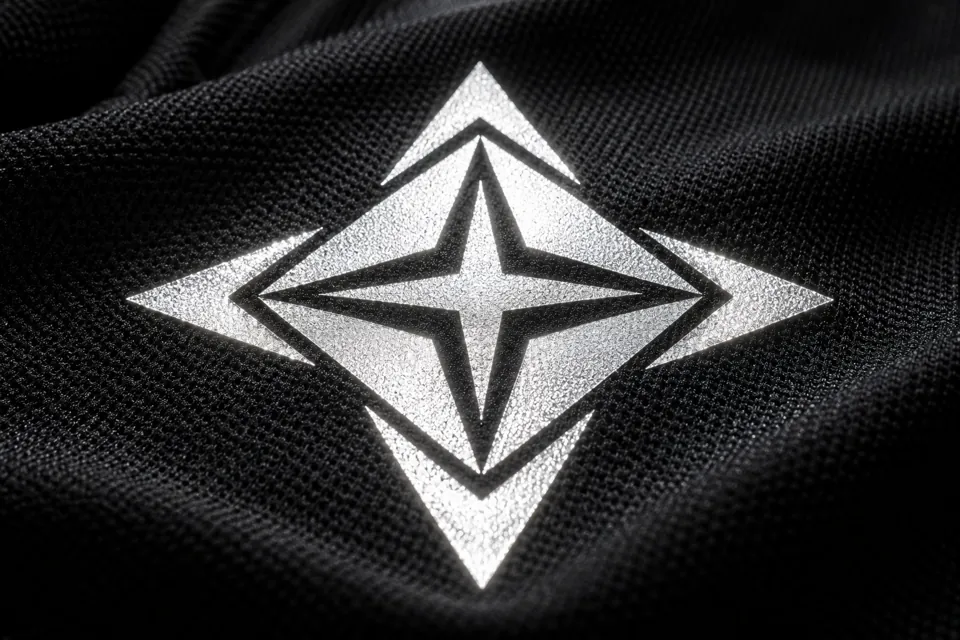 Illustrative silver reflective geometric graphic catching light on black technical fabric